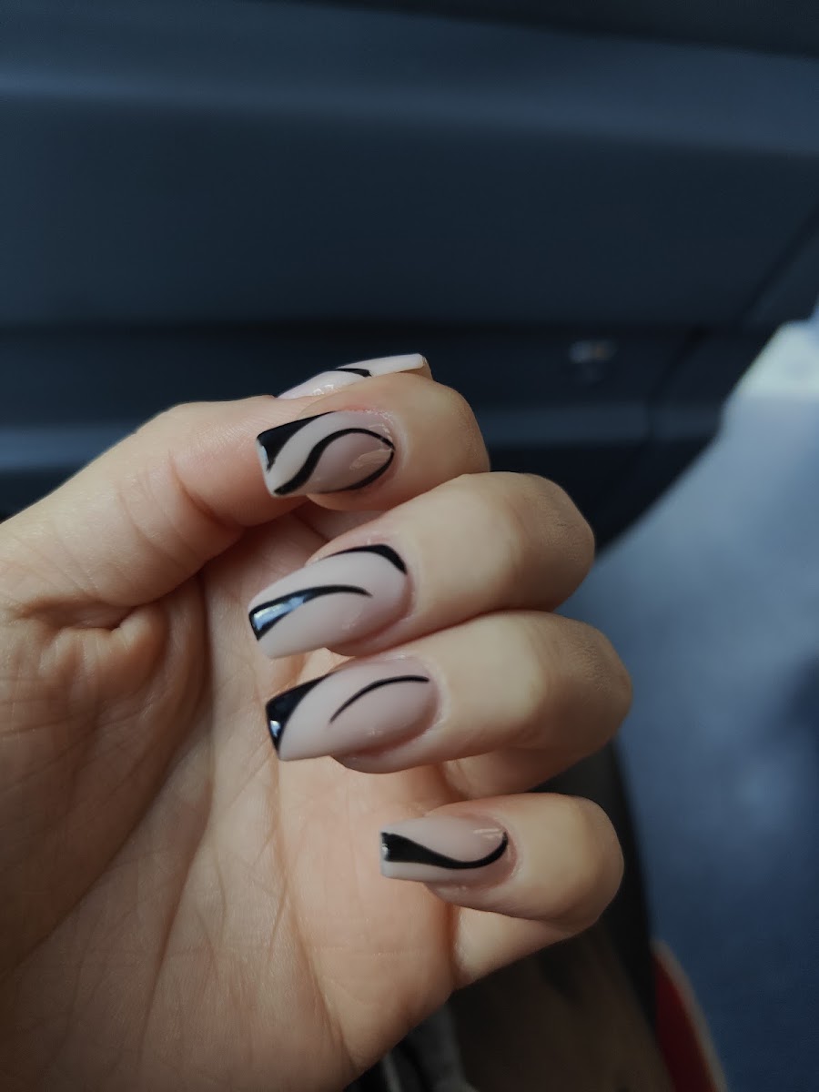 Manicura con diseño de líneas curvas negras asimétricas sobre base nude