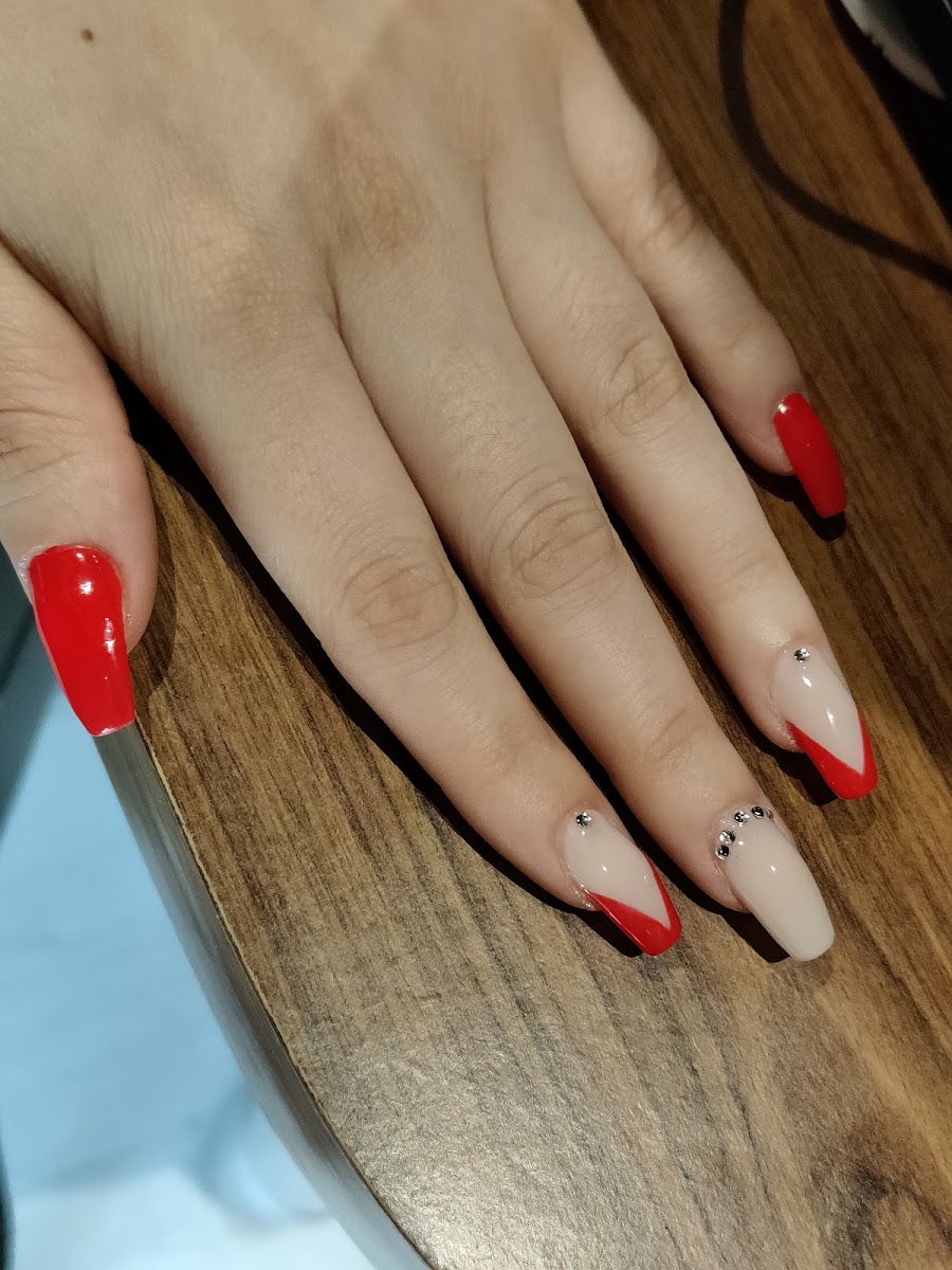 Uñas estilo stiletto con diseño rojo y nude con pequeños cristales decorativos