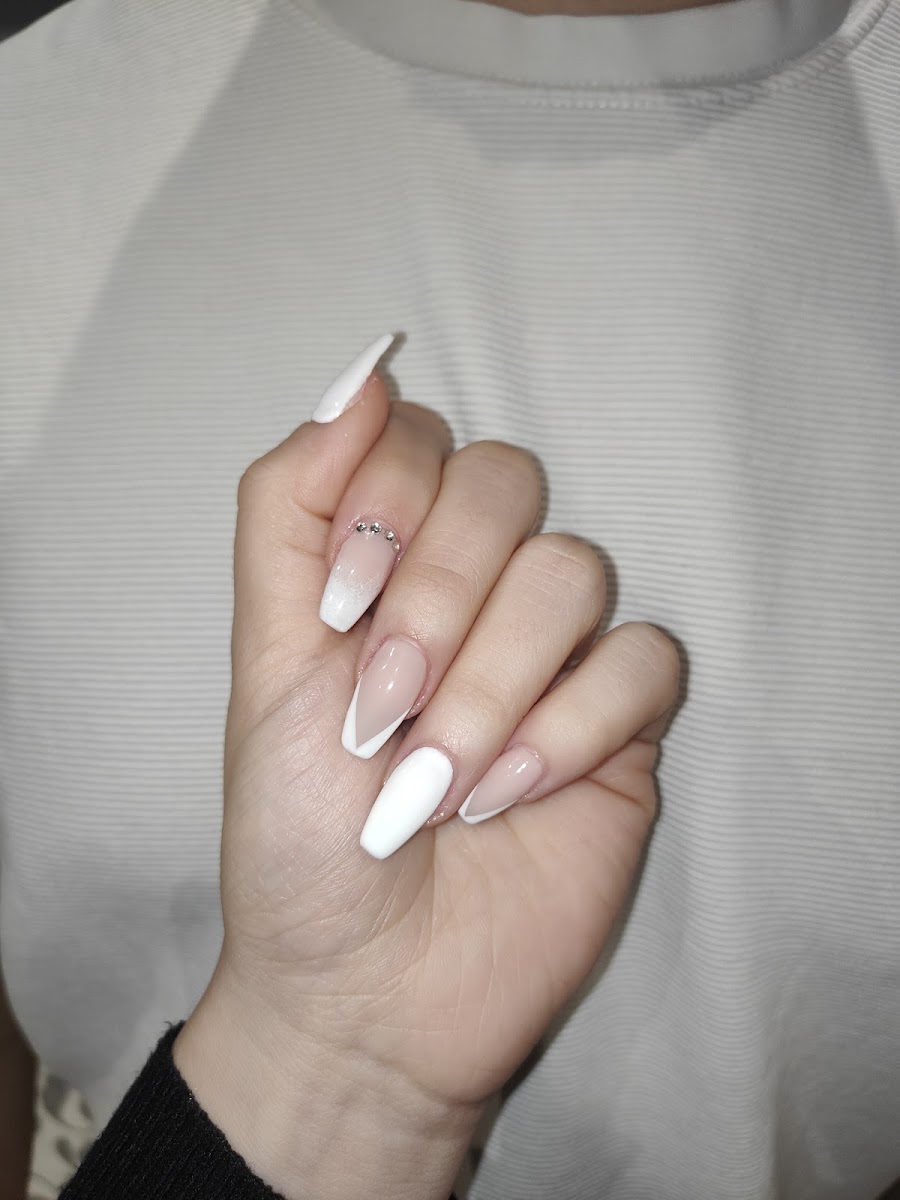 Uñas largas ovaladas con diseño blanco y nude degradado, anillo con cristales en el dedo medio