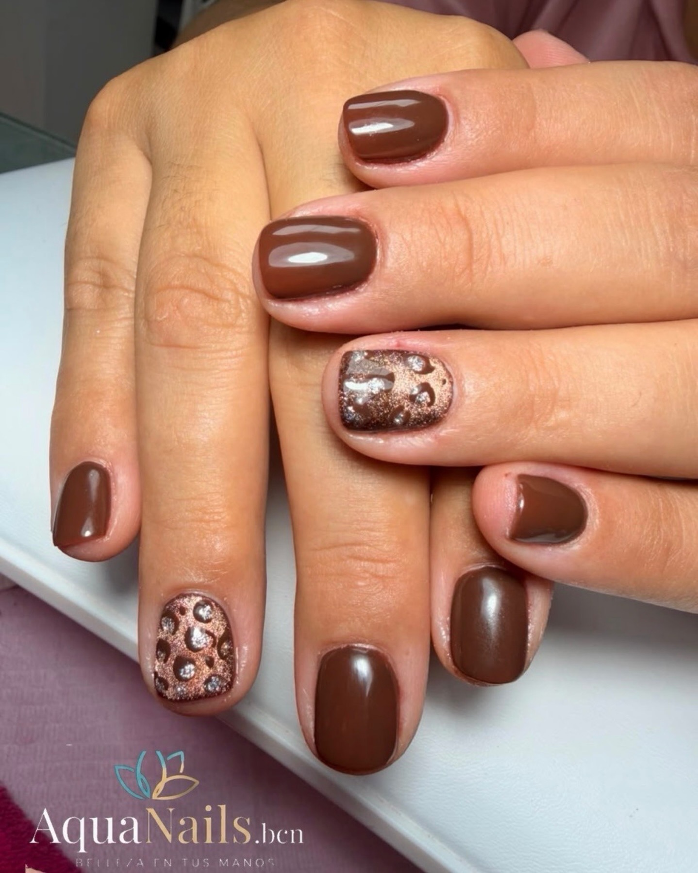 Uñas cortas en marrón chocolate con diseño de leopardo en un dedo