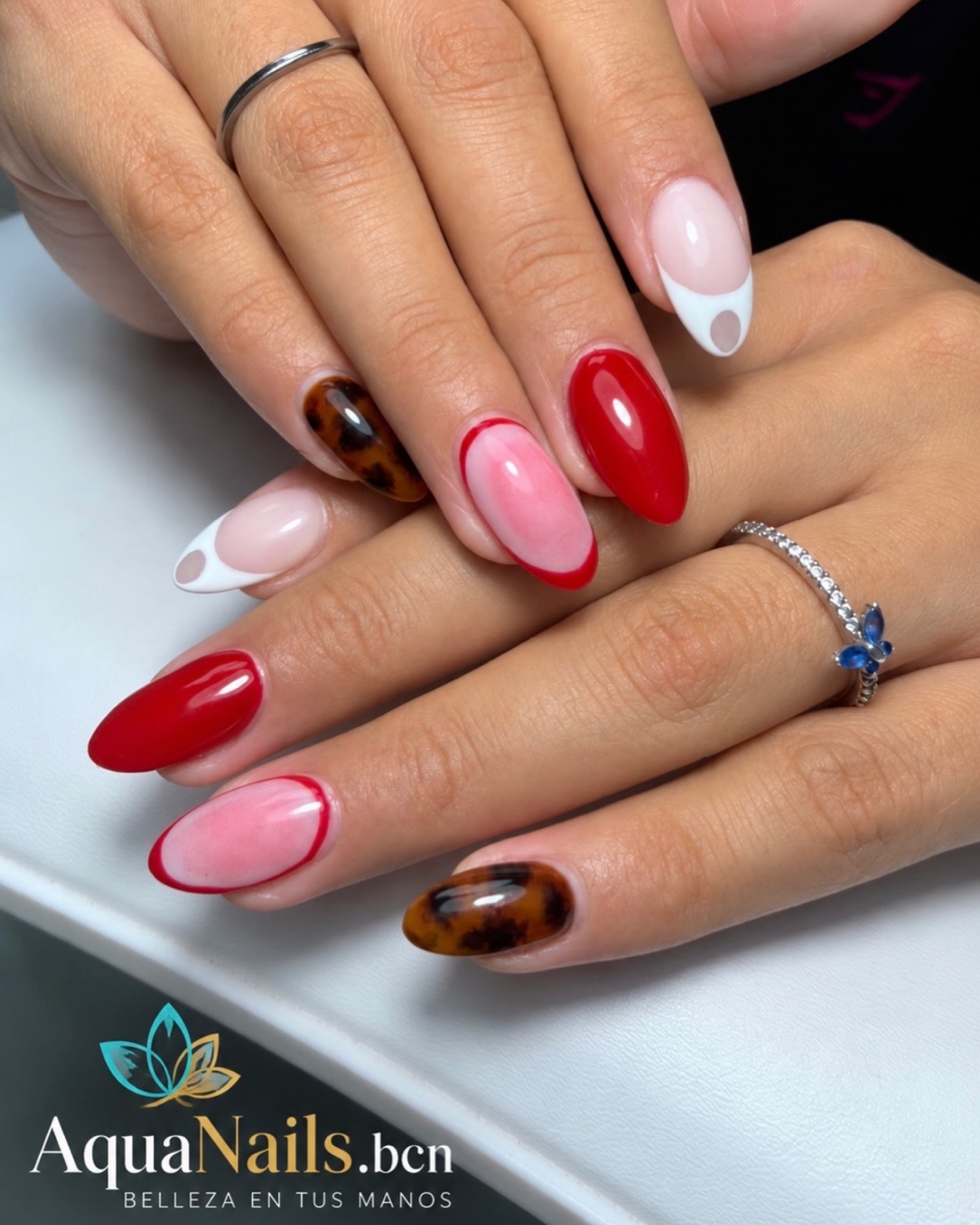 Uñas largas con diseño variado: rojo, rosa con borde rojo, tortuga y blanco con lunares grises