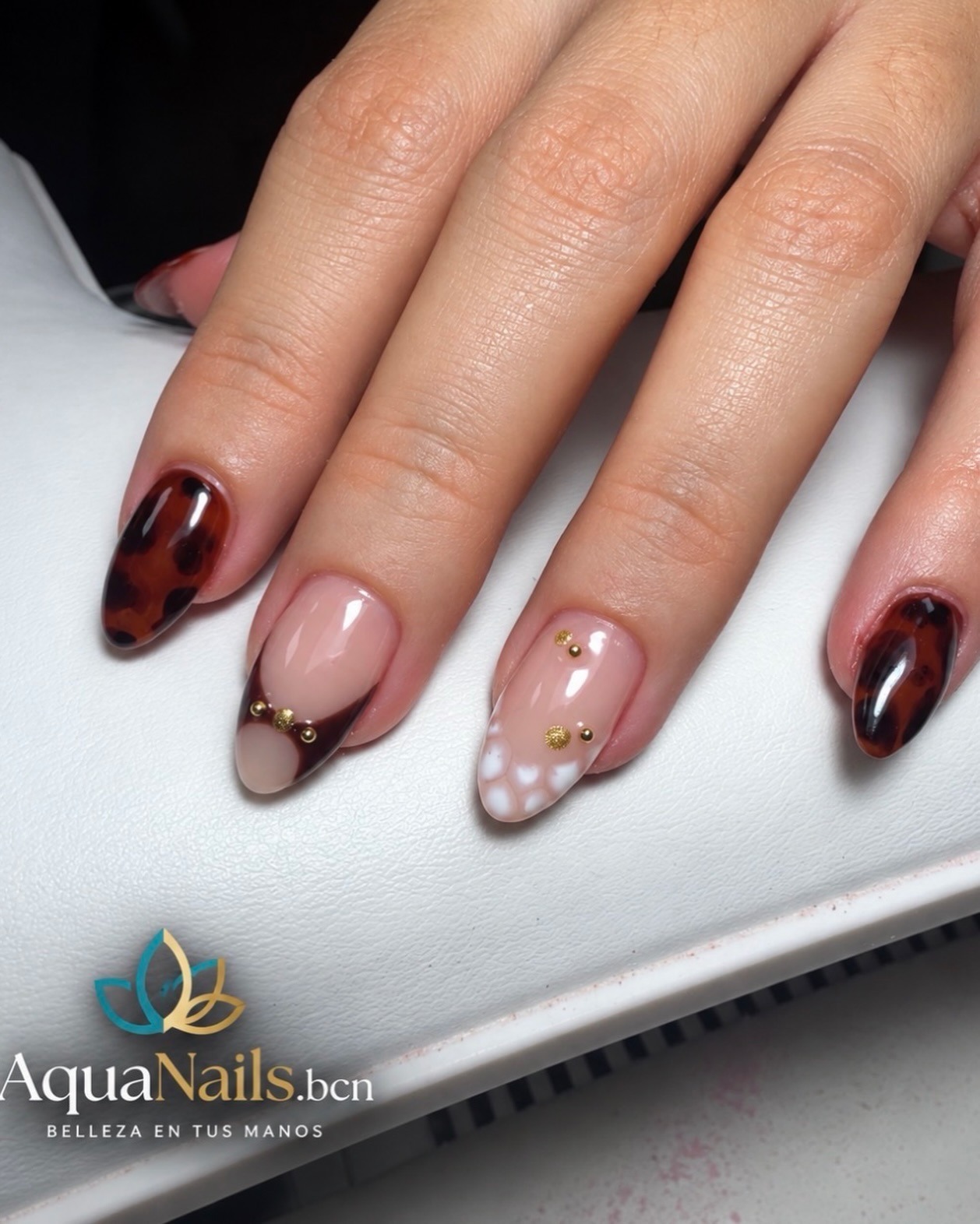 Uñas almendradas con diseño de tortuga carey, rosa nude y lunares blancos con tachuelas doradas